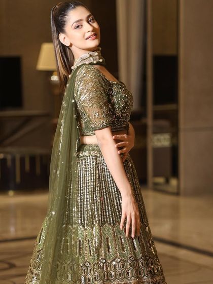 A side profile of the olive green lehenga, showing the delicate dupatta and the intricate embroidery on the back of the blouse.
