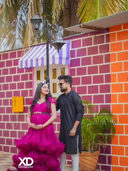 A candid shot of a couple sharing a look, set against a colorful pink and purple brick wall.