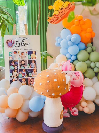 A personalized milestone board for Eshan's first birthday, set against a backdrop of Pooh-themed decorations.