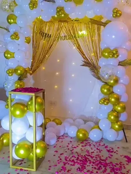 A close-up of the white and gold anniversary backdrop, featuring a golden curtain and fairy lights for a warm glow.