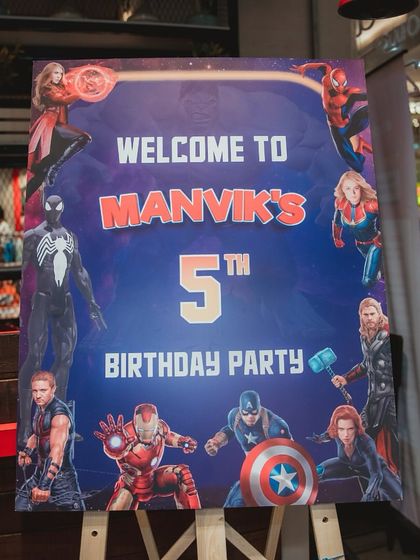 A welcome sign for Manvik's 5th superhero birthday party, featuring a full roster of Avengers characters.