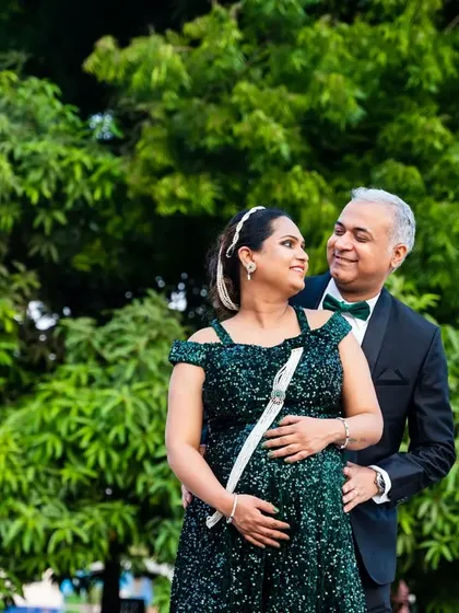 An elegant couple portrait set against a backdrop of lush green trees. Their formal attire adds a touch of sophistication to this outdoor shoot.