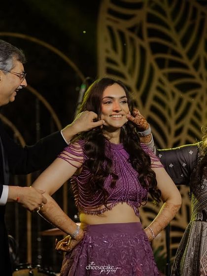 The bride's parents playfully pinching her cheeks during the Sangeet night, a super sweet family moment.