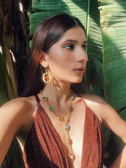 Another look from the Tirbari campaign, showcasing a long, elegant gemstone necklace against a simple bronze dress.