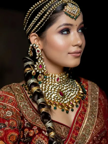 A side profile of a regal bride, highlighting the intricate braided hairstyle and the stunning details of her polki and ruby jewelry.
