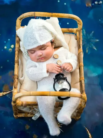 A dreamy newborn portrait with a celestial theme. This little one is sleeping soundly in a basket, floating among the moon and stars.