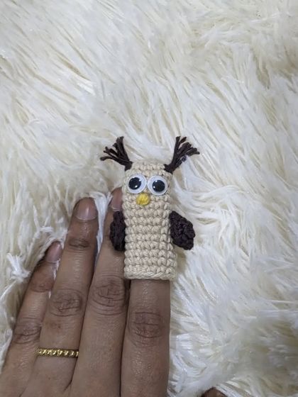 A close-up of the owl finger puppet, with big googly eyes and tufted ears.