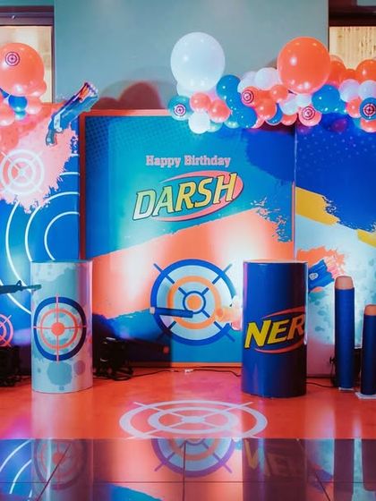 The full view of the action-packed Nerf Gun party stage. The setup includes balloon columns, target-themed floor decals, and a silhouette of a soldier for a complete battle zone feel.