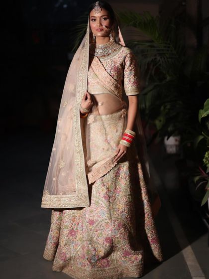 The full bridal look, complete with traditional red bangles, against the soft elegance of the pastel lehenga.