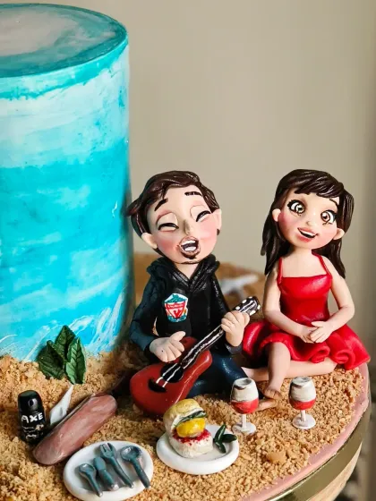 The finished couple topper on the beach-themed cake, surrounded by all their favorite things.