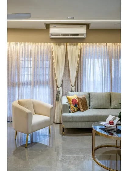 The elegant armchair with gold-finished legs provides a cozy reading spot. Layered curtains offer both privacy and soft, diffused light, enhancing the room's calm ambiance.