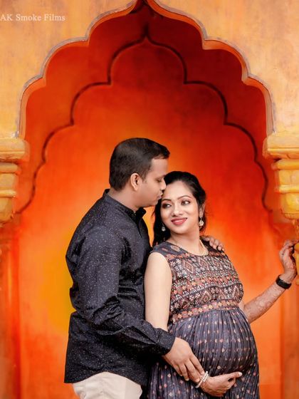 A tender moment between the couple in the same beautiful archway setting. A gentle kiss on the forehead adds a touch of romance to this styled maternity portrait.