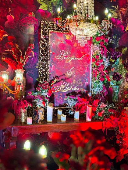 Another angle of the stunning welcome area, showcasing the custom-printed floral backdrop that tied the entire red-themed decor together. The ornate frame and soft lighting made it a popular photo spot for guests.