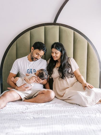 A family with their newborn baby on the bed. The mother is still glowing from her pregnancy, creating a beautiful "before and after" story.