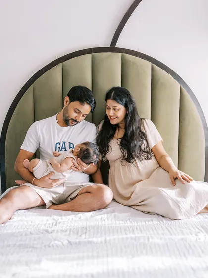 A family relaxing on their bed with their new baby. At-home sessions are perfect for capturing these comfortable, everyday moments of love.