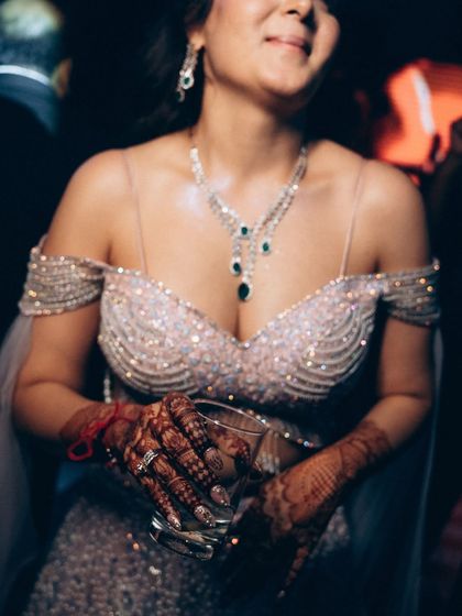 A close-up on the bride's stunning reception outfit and henna-adorned hands. This shot highlights the beautiful details and the relaxed, happy vibe of the party.