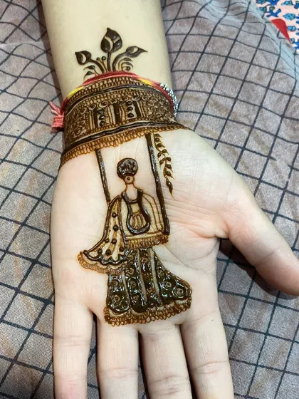 A close-up of a simple yet charming Teej motif. This design shows a woman on a swing, perfect for someone who wants a touch of festive art without full coverage.
