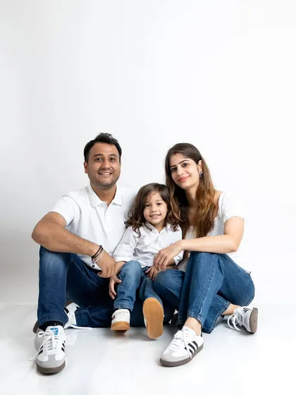 A classic seated family portrait. The simple white and denim outfits keep the focus on the family's happy connection.
