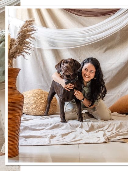 A joyful portrait of Tofu the chocolate Labrador and his mom, both smiling for the camera in their custom-built home studio.