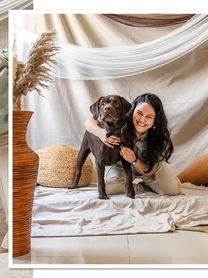 A joyful portrait of Tofu the chocolate Labrador and his mom, both smiling for the camera in their custom-built home studio.