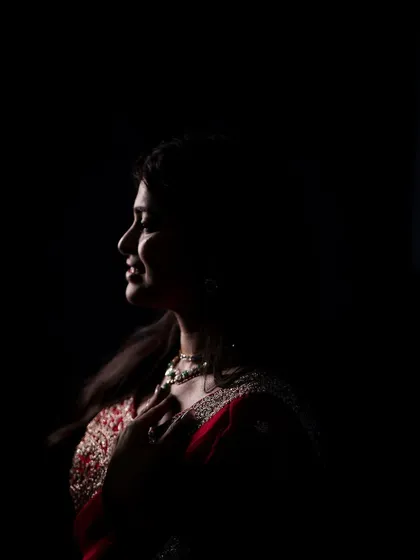 We use light and shadow to sculpt a portrait. This low-key image highlights the bride-to-be's profile and the intricate details of her attire, creating a moody and artistic photograph.