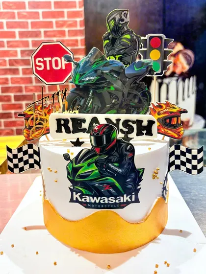 A high-energy Kawasaki motorcycle-themed cake, complete with bikers, traffic lights, and checkered flags for a true racing fan.