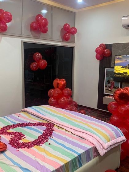 A cozy and romantic room decoration with red balloons and a heart made of rose petals on the bed. This simple yet effective setup is perfect for a birthday or anniversary surprise.