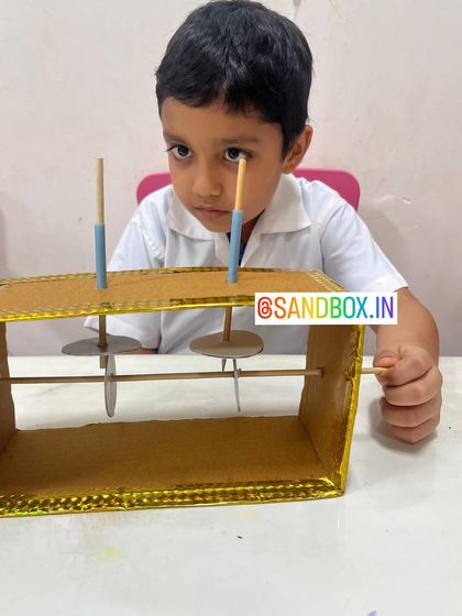 We introduce the fundamentals of engineering with simple machines. This student is focused on building a mechanism with axles and wheels, learning about how parts work together to create movement.