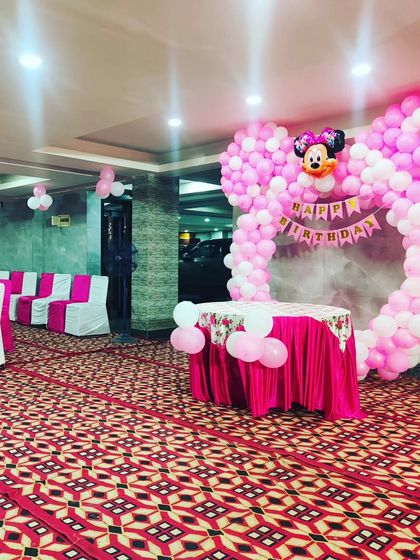 Another view of the Minnie Mouse birthday party setup, showing the cake table and balloon arch in relation to the guest seating area.