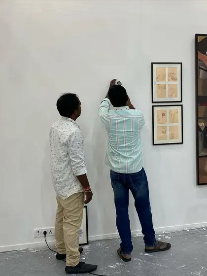 The team hanging smaller works by Gulammohammed Sheikh at Art Mumbai.