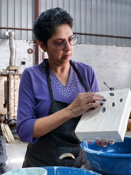 A student meticulously cleans excess glaze from her piece. This ensures a clean finish and prevents the pot from sticking to the kiln shelf.