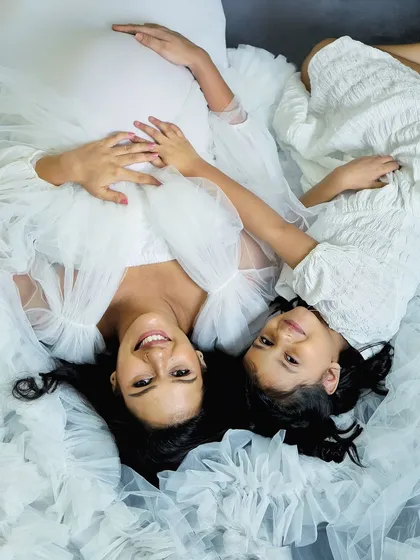 An artistic top-down shot showing the beautiful connection between a mother and daughter. The flowing white fabric creates a soft, dreamy atmosphere for this maternity portrait.