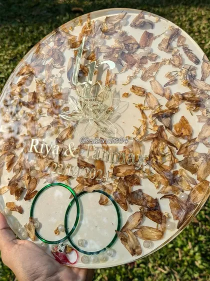 This set includes a large 12-inch circular plaque and a matching 4-inch coaster, which can also be a fridge magnet. Both pieces preserve the couple's wedding flowers and bangles.