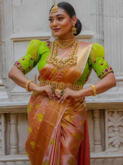 A close-up of the model, showing the intricate details of the layered necklace and the peacock-themed vaddanam.