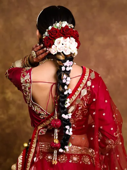 A hairstyle can complete the entire bridal look. For this bride, we created a stunning traditional long braid using extensions and adorned it with fresh red and white roses, adding a touch of romance and elegance.