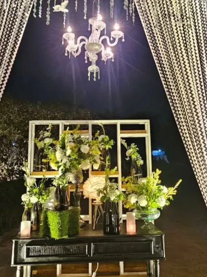 A detail shot of our black and white themed decor. This console table setup includes a modern white frame, black vases with white flowers, and a crystal chandelier, showing our attention to chic, coordinated details.