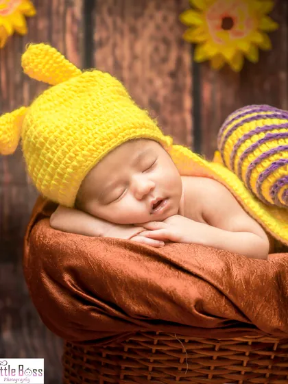 A close-up of the baby snail, showing the details of the hand-knitted costume and the baby's peaceful sleep.