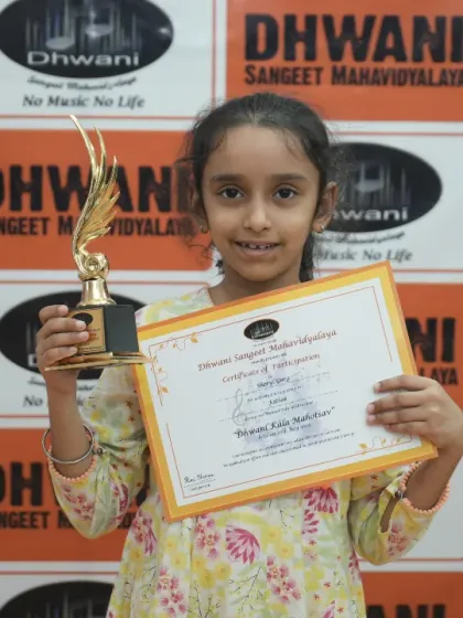 A young student proudly holds her certificate and trophy.