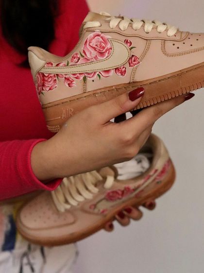 Holding up the finished tea-dyed floral AF1s. The combination of the soft-toned base and the pink roses creates a very romantic and elegant custom sneaker.