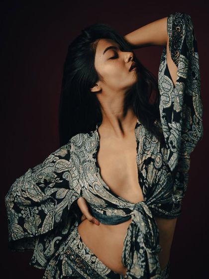 A powerful and sensual pose that highlights the model's form and the flowing fabric of the outfit.