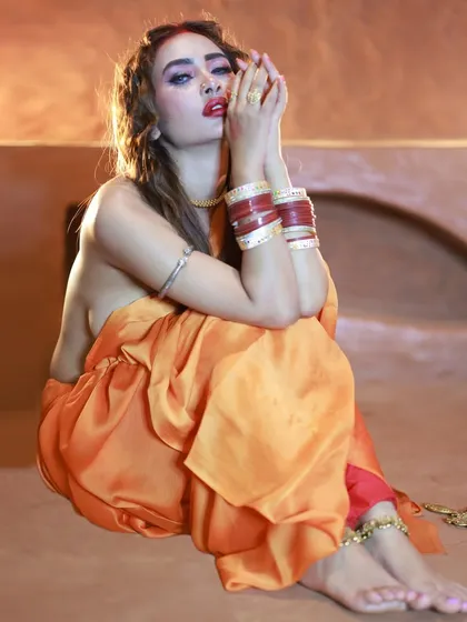 This seated pose highlights the beautiful fall of the saree fabric and the intricate anklets. The lighting creates a warm, earthy mood that matches the theme.