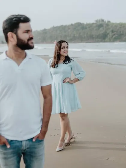 A creative pose with the groom in the foreground and the bride in the background, adding depth and interest to this beach portrait.