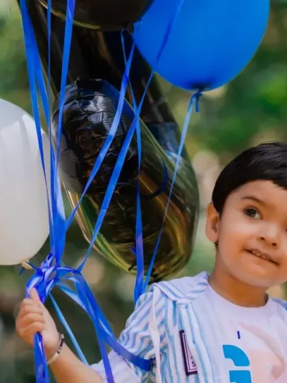A candid moment of a little boy holding balloons in the park. We love capturing these simple, happy memories.