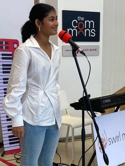 A student singer looking confident and happy on stage at the Museum of Solutions. We celebrate every student's journey and their courage to perform.