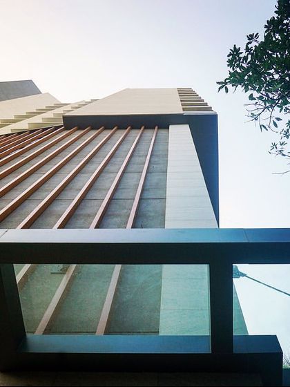 A low-angle shot of the façade, emphasizing the texture of the wooden fins and the modern architectural form of the residential building.