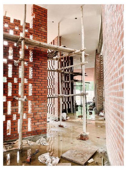 An interior view of the jali walls during construction, showing how light filters through the perforations.