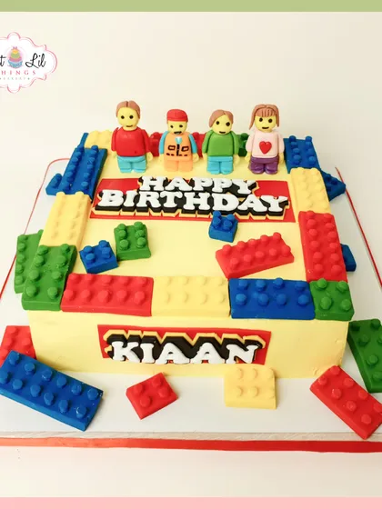 A classic LEGO-themed cake designed for Kiaan's birthday. This rectangular cake is covered in colorful, edible fondant blocks and topped with custom LEGO-style family figures, making it a personal and fun celebration centerpiece.