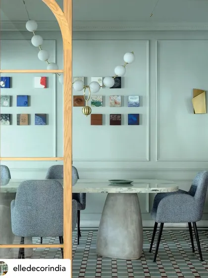 This dining room from 'Summer Haus' is defined by its sophisticated palette and custom details. A sculptural concrete-base table is surrounded by soft grey chairs, set against patterned floor tiles and a modern globe chandelier, creating an elegant space for formal dining.