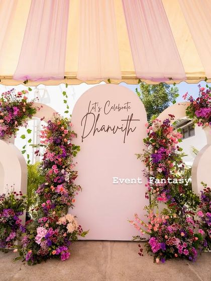 For a modern take on a naming ceremony, I created this lovely pastel-themed stage. The design features a series of white arches adorned with beautiful arrangements of pink and purple flowers, creating a fresh and celebratory look.