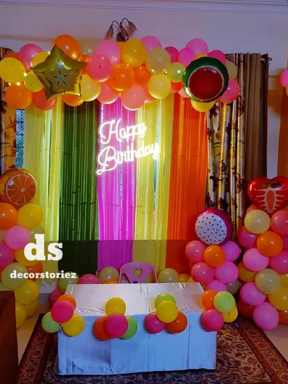 Another perspective of the fruit-themed decor, showing the full arrangement of the colorful balloon columns and backdrop.